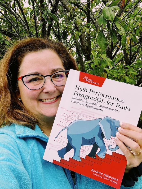 Claire holding a copy of High Performance PostgreSQL for Rails